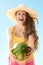 Cheerful healthy woman playing with watermelon against blue sky