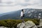 Cheerful hiker girl with dark hair on high mountains background in summertime