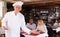 Cheerful hospitable chef inviting to cozy pizzeria