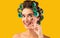 Cheerful Housewife Holding Eyelashes Curler Posing Over Yellow Background, Studio