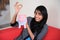 Cheerful Indian girl holding coin and piggybank