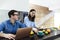 Cheerful intelligent couple working together at home kitchen during breakfast with laptop