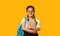 Cheerful Japanese School Girl Hugging Book Standing Over Yellow Background