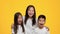 Cheerful Japanese siblings having fun grimacing showing tongues, yellow background