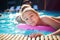 Cheerful kid, boy having fun swimming in the pool with inflatable board, summer activity