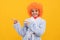 cheerful kid in fancy orange wig hair wear home bathrobe directing on copy space, promotion