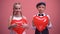 Cheerful kids in love holding red heart-shaped balloons and smiling to camera