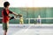 Cheerful kids playing tennis on court