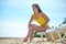 Cheerful lady seated on the deckchair using the sun lotion