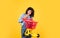 cheerful lady in shirt denim style carry shopping trolley on yellow background, shopping