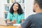 Cheerful latin american female nurse or young doctor listening to patient