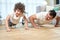 Cheerful latin boy smiling at camera while exercising together with his sportive middle aged father, doing push ups at