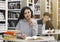 Cheerful latin girl sitting at desk in library