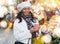 Cheerful Latina with cup of hot tea walking at Christmas street fair
