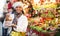 Cheerful Latina looking for New Year decorations in street market