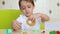 A cheerful, laughing boy plays with a modeling mixture for work. Child sculpts platinina sitting at the table.