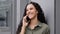 Cheerful laughing smiling happy carefree woman in city outdoors answer call talking conversation by smartphone chatting