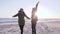 Cheerful leisure, youth running around and waving hands at beach in sun beams