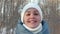 cheerful lifestyle woman in a down jacket and a white hat in a winter Park on a Sunny day