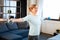 Cheerful light-haired mature woman staying in living room