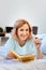 Cheerful light-haired woman resting on her bed and reading interesting book