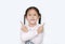 Cheerful little Asian kid girl cross arms and pointing two forefinger to the side over white background