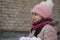 Cheerful little beautiful smiling girl in warm clothes and a knitted hat will hold a lot of snow in her hands against the