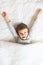 Cheerful little boy in bed with alarm clock, wake up morning concept, sleeping time