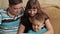 Cheerful little boy and his parents sitting on sofa while using digital tablet