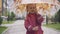 Cheerful little Caucasian girl spinning umbrella outdoors. Portrait of smiling cute child enjoying spring or autumn day