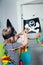 Cheerful little child in a pirate costume sets a black pirate flag. Close-up. Children`s birthday party. Fun games at home with