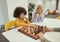 Cheerful little diverse boys sitting at the table and playing chess in school