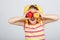 Cheerful little girl with apples, lemon and banana poses positively in studio