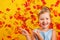 Cheerful little girl in a costume of Princess Cinderella on a background of falling autumn leaves.