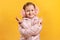 A cheerful little girl has crossed her arms and is showing a victory sign with her fingers.