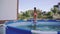 Cheerful little girl is having fun in the outdoors swimming pool. Slow Motion 240 fps. Child is jumping and playing in