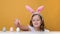 Cheerful little girl hunts on Easter holiday. The child gets out from under the table and grabs the egg.