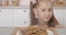 Cheerful little girl peeking out of table and taking sweet tasty cookie from plate. Portrait of charming pretty