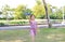 Cheerful little girl raise up a blue toy airplane flying on air in the garden outdoor