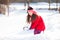 Cheerful little girl shoveling snow in winter park