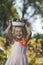 Cheerful little girl with a smile holds a plate of vegetables on her head. Rural harvesting