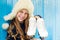 Cheerful little girl in warm sweater and hat keeps figure skates