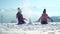 Cheerful little girls in outwear having fun and throwing snow in sunlight standing outdoors