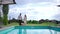 Cheerful loving carefree couple walking in slow motion to swimming pool at tourist resort outdoors. Wide shot portrait