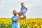 Cheerful loving father with his son on vacation in the field with sunflowers