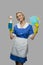 Cheerful maid in uniform holding rags and detergent.