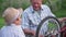 cheerful male child, together with caring grandfather, repairs bicycle wheel while walking outside city