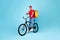Cheerful Male Courier With Bike Gesturing Thumbs Up, Blue Background