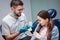 Cheerful male dentist hold artificial jaw with teeth in hands. He show it to small girl and smile. Child look amazed