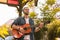 Cheerful male guitarist learning play on street